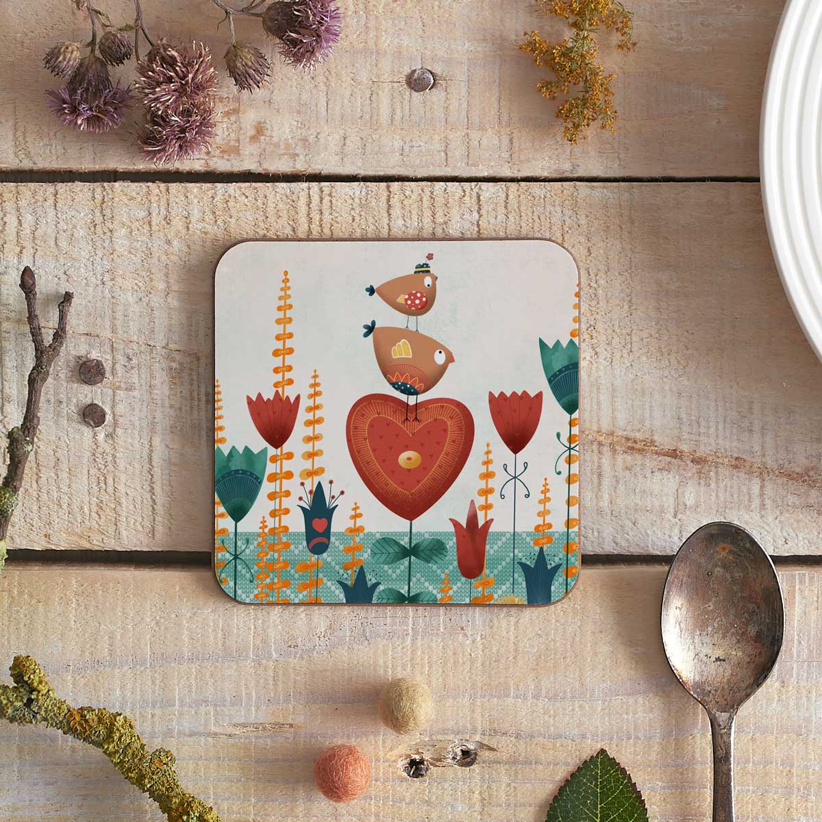square coaster with illustration of two birdies stood on a heart shaped flower