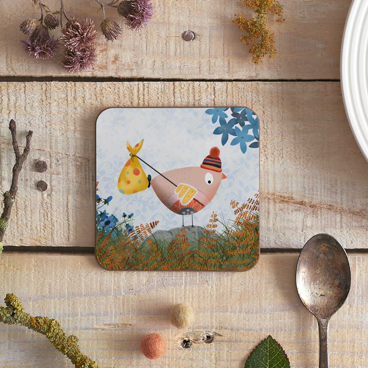 square coaster with illustration of a birdie going on an adventure