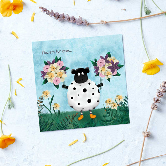 greeting card with a sheep holding two bunches of flowers