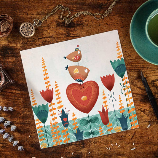 greeting card with illustration of two Birdies sat on top of a heart shaped flower