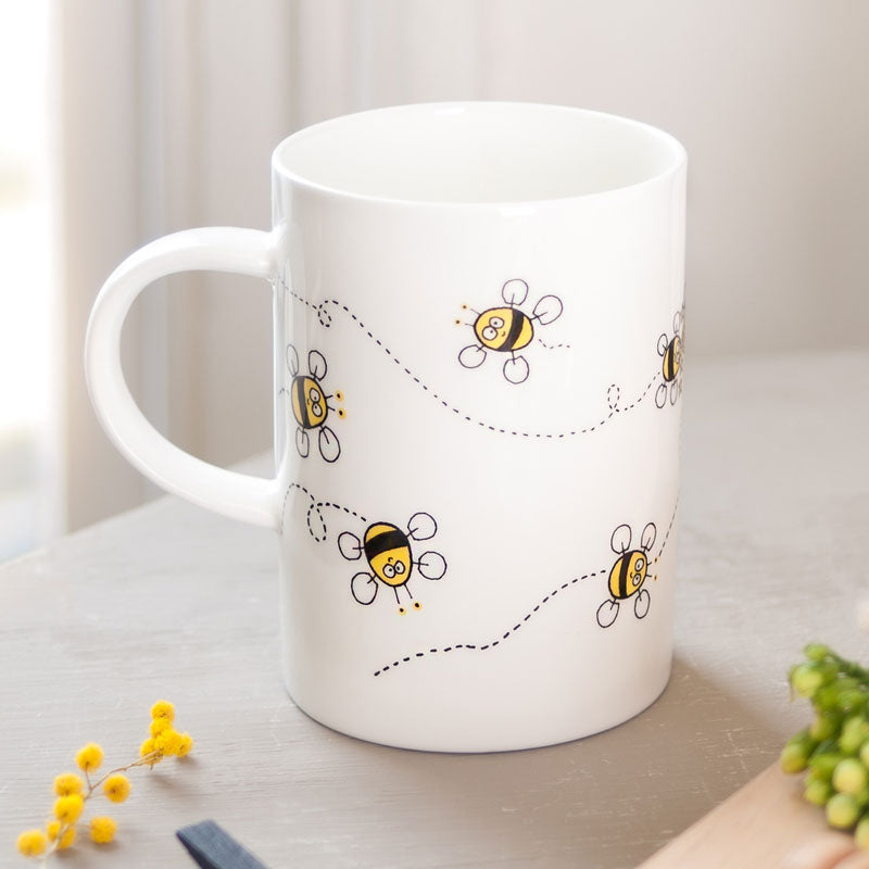 White mug with bee illustrations on a light surface
