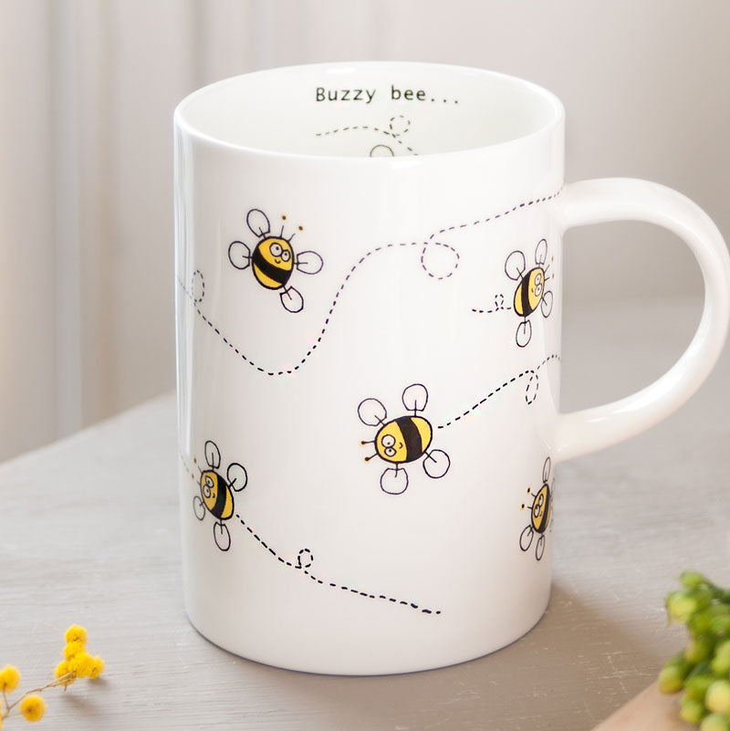 Close up of the front of a white mug with bee illustrations 