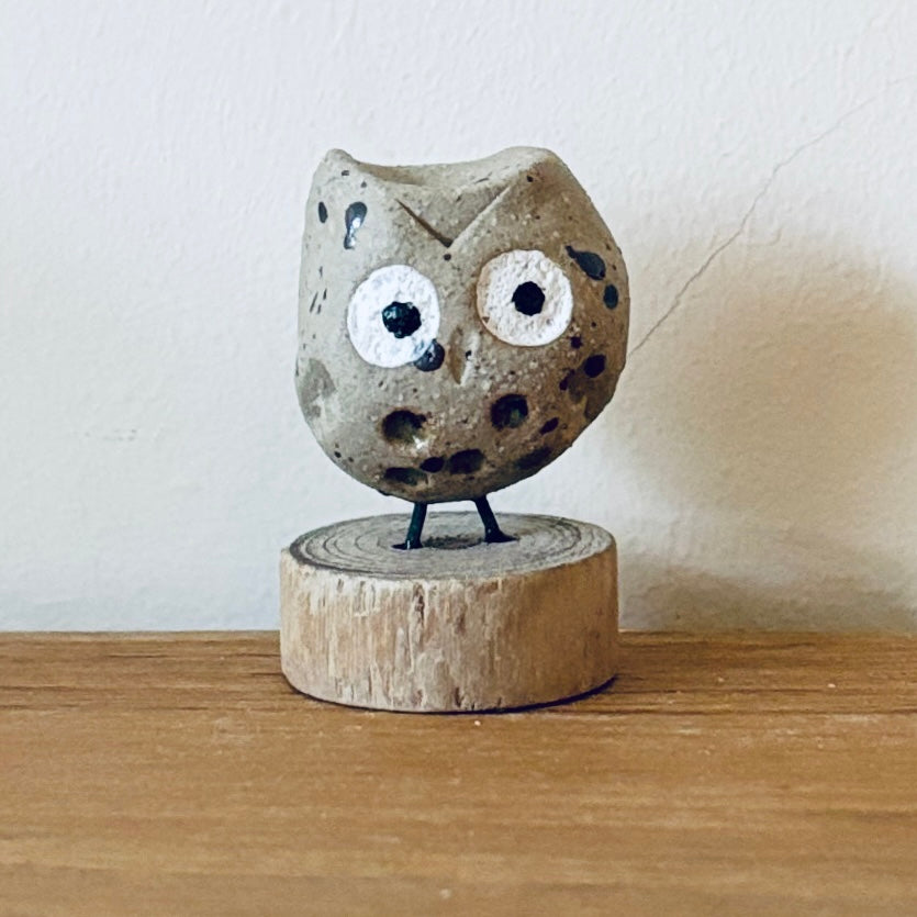 Tiny ceramic owl stood on a little slice of wood