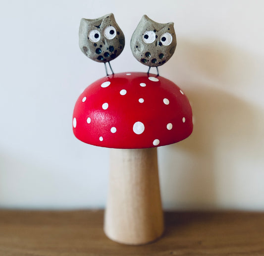 A couple of loved up ceramic owls sat on a hand painted wooden toadstool