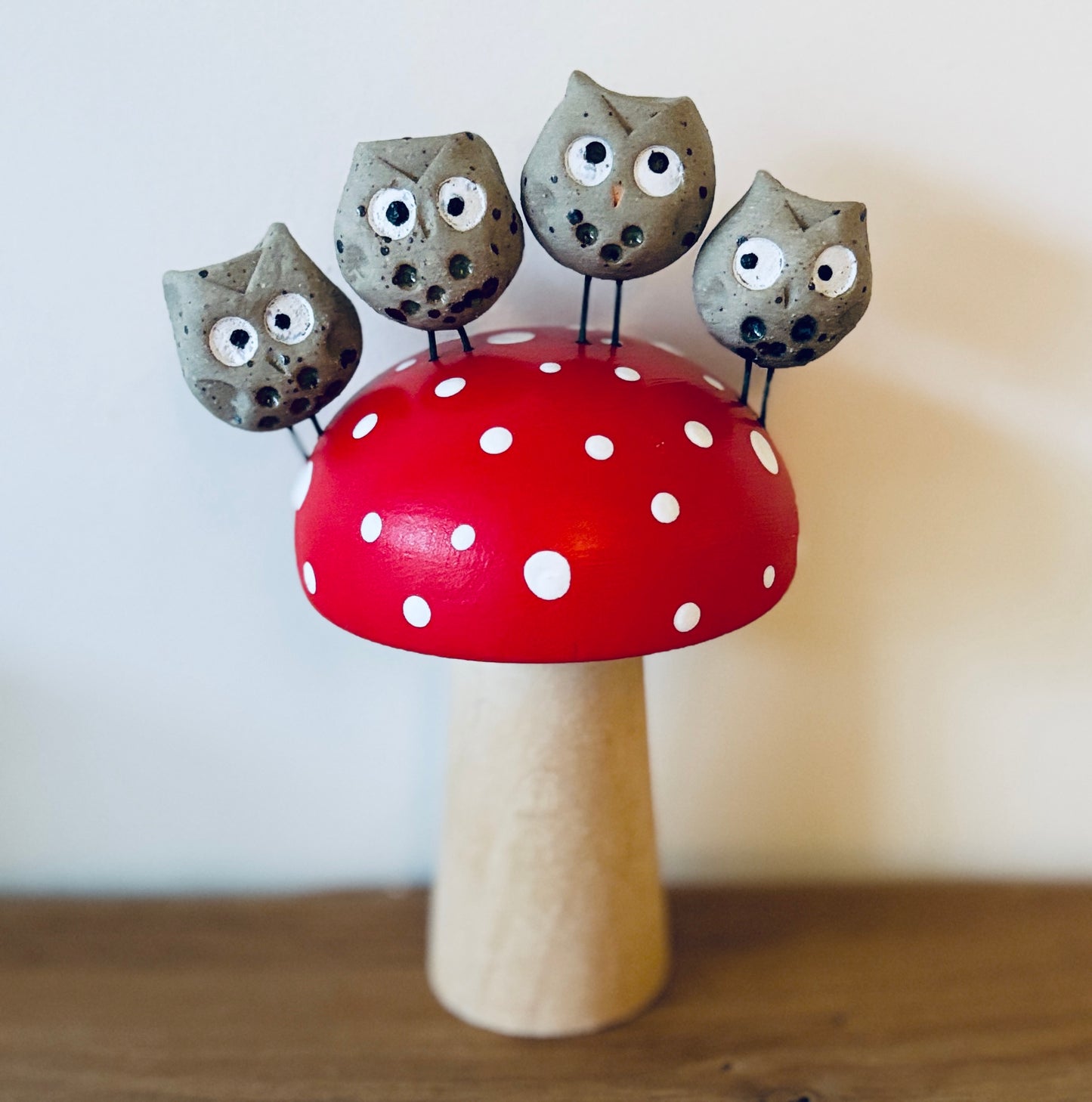 A handpainted wooden toadstool with 4 mini clay owls perched on it