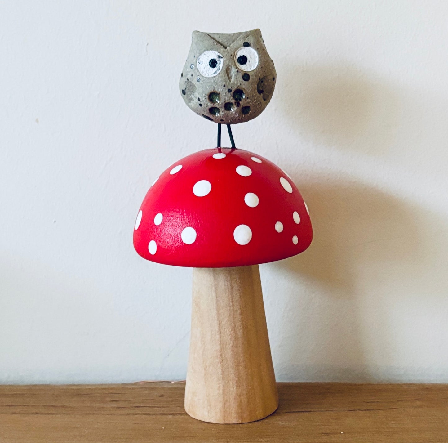 A little ceramic owl sat on a hand painted wooden toadstool