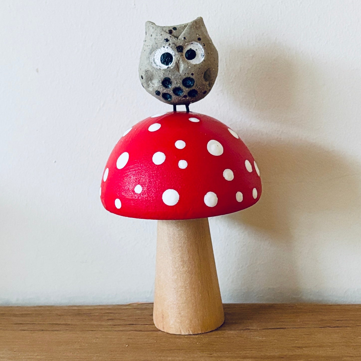 A little ceramic owl sat on a hand painted wooden toadstool