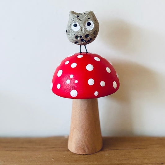 A little ceramic owl sat on a hand painted wooden toadstool