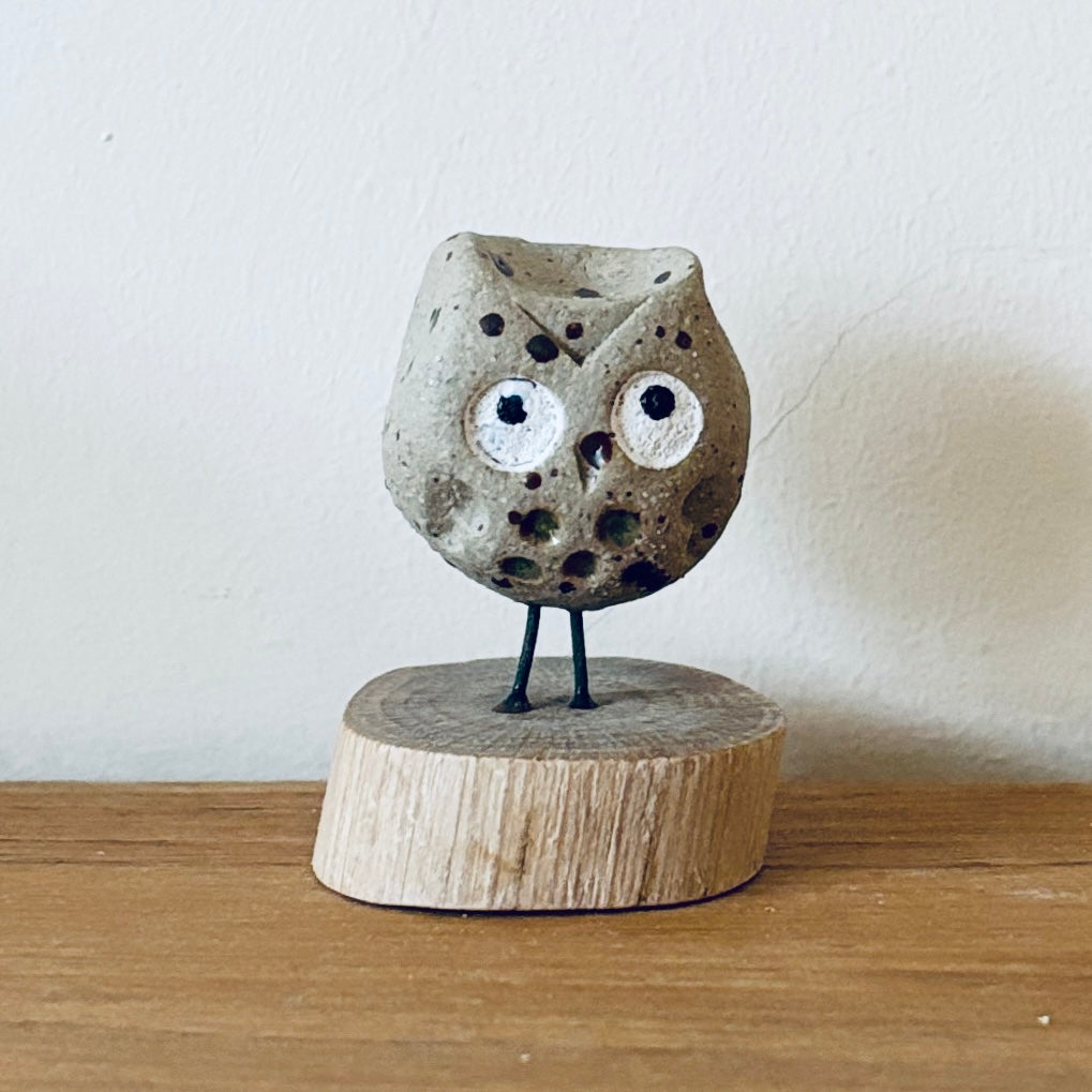 Tiny ceramic owl stood on a little slice of wood