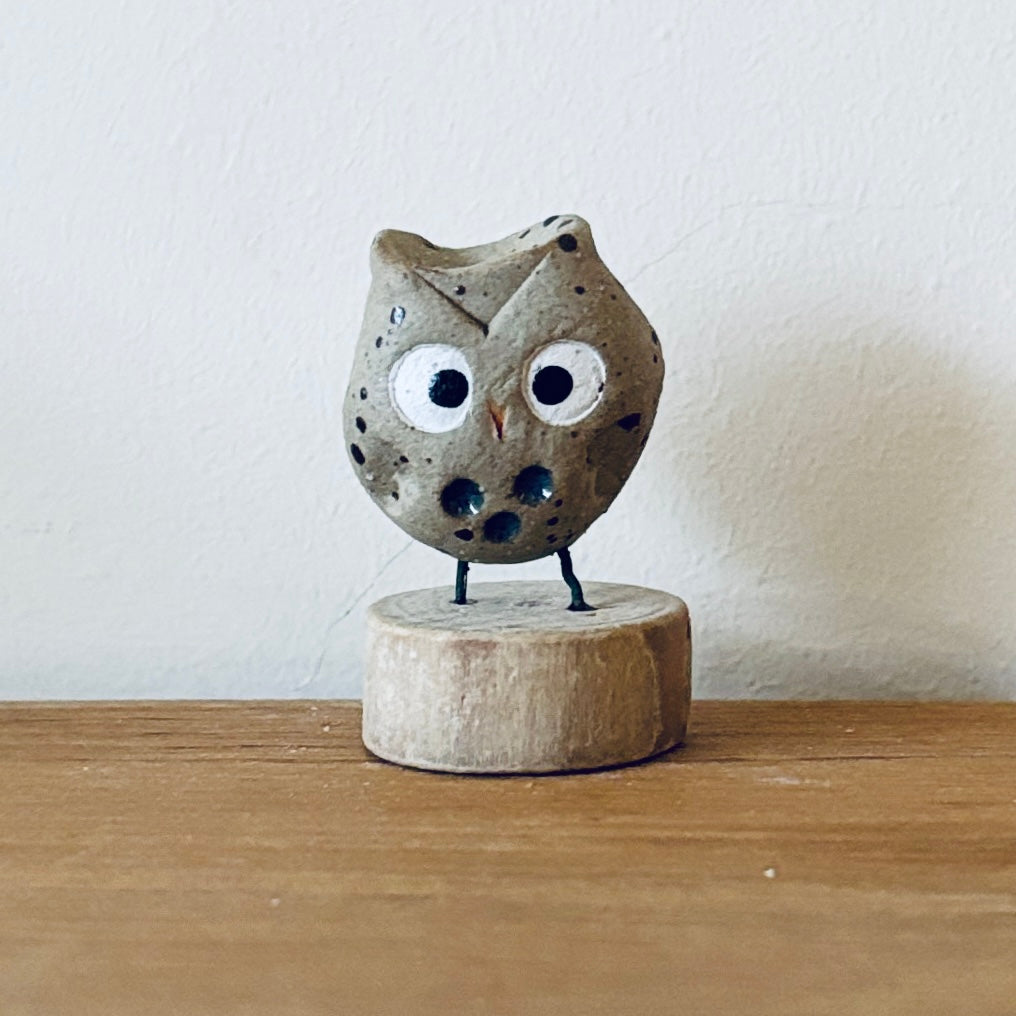 Tiny ceramic owl stood on a little slice of wood