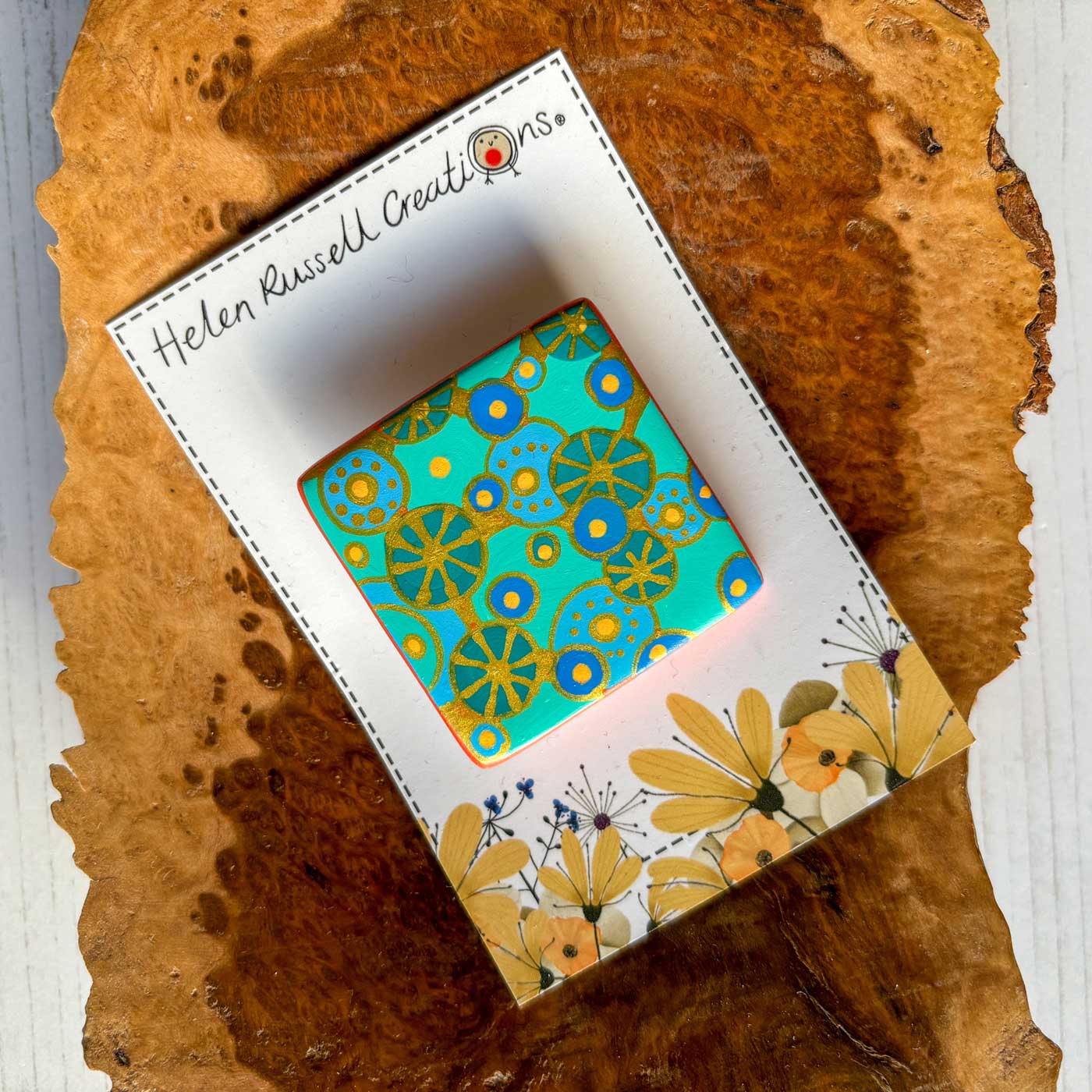 square ceramic brooch with coral reef inspired pattern in blues, greens and gold