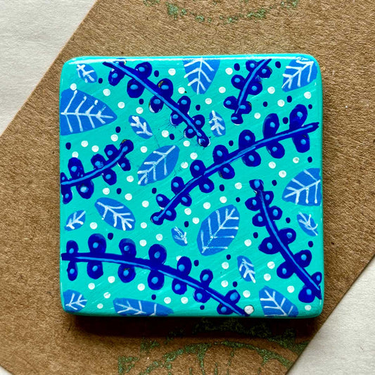 square ceramic brooch with leaf and bracken illustration in blues