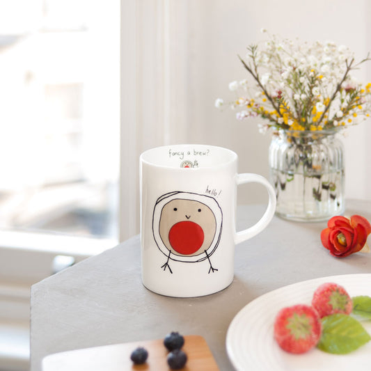 Mug with a bird design on a table with flowers and food