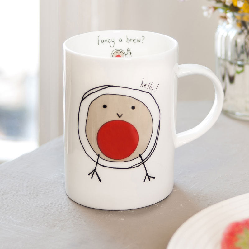White mug with a cartoon robin design and text on a light surface.