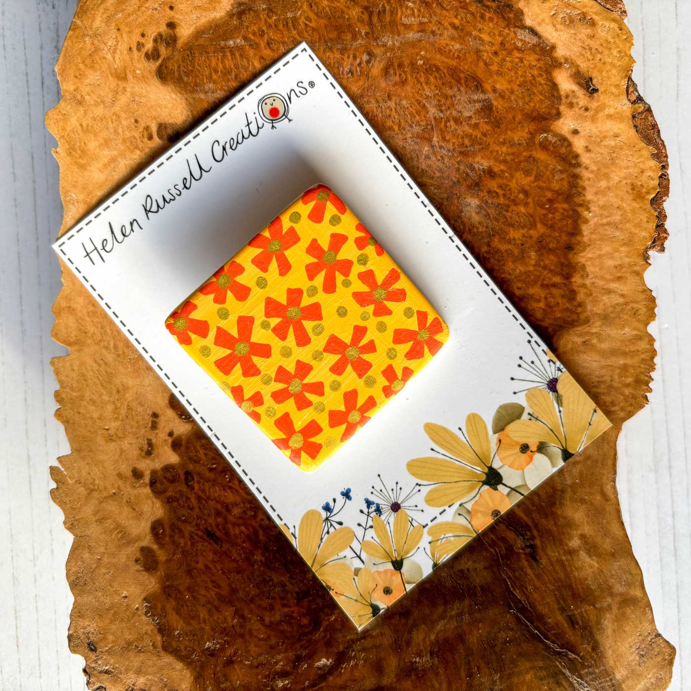 square ceramic brooch hand painted with a simple yellow and orange floral pattern