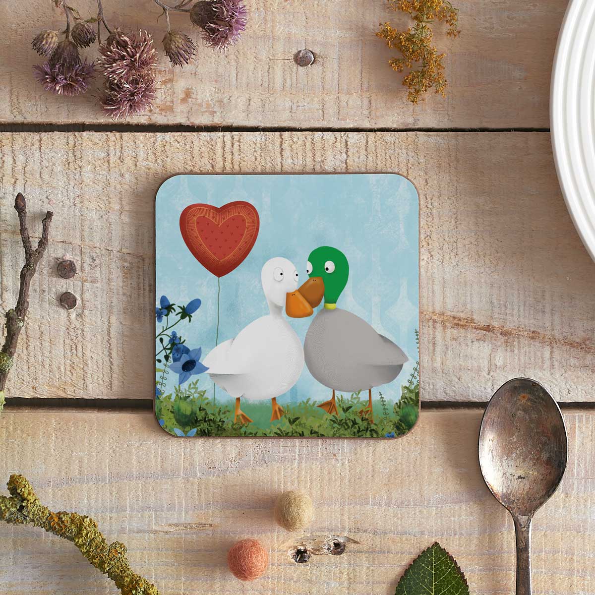 square coaster with two illustrated ducks and a heart