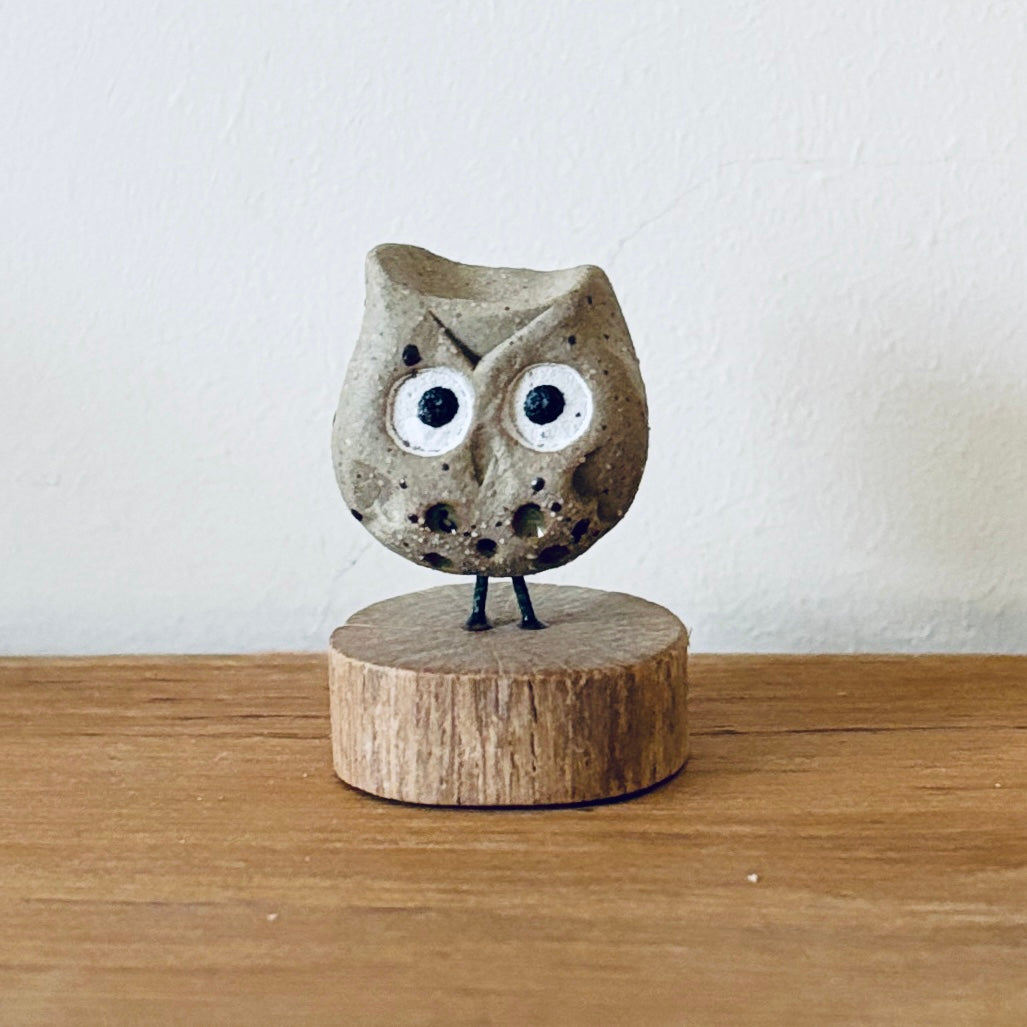 Tiny ceramic owl stood on a little slice of wood