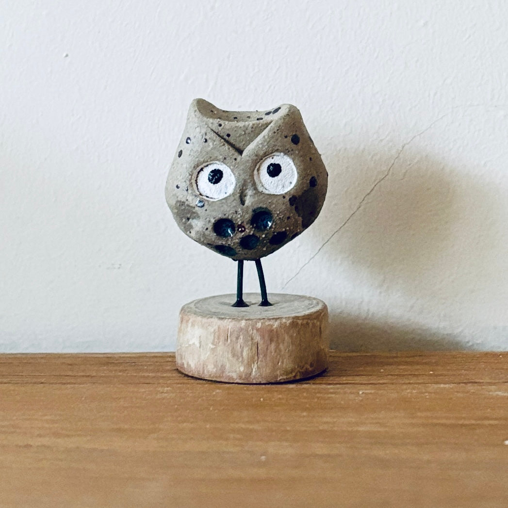 Tiny ceramic owl stood on a little slice of wood