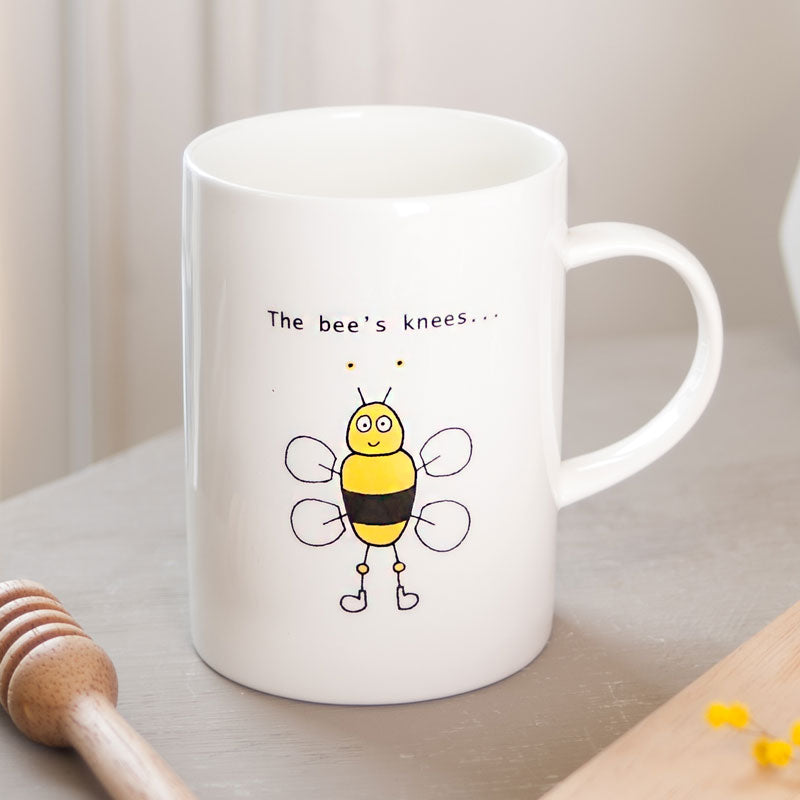 Close up of white china mug with illustration of a bee with yellow knobbly knees