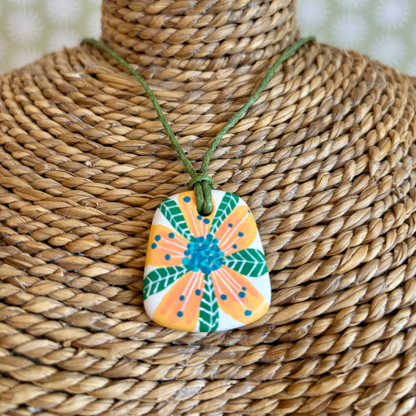 Hand painted ceramic pendant which a peach and green tropical flower