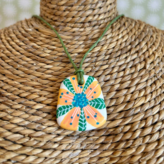 Hand painted ceramic pendant which a peach and green tropical flower