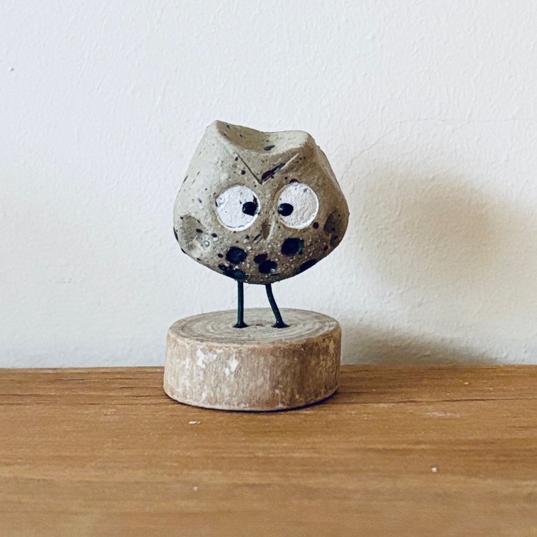 Tiny ceramic owl stood on a little slice of wood