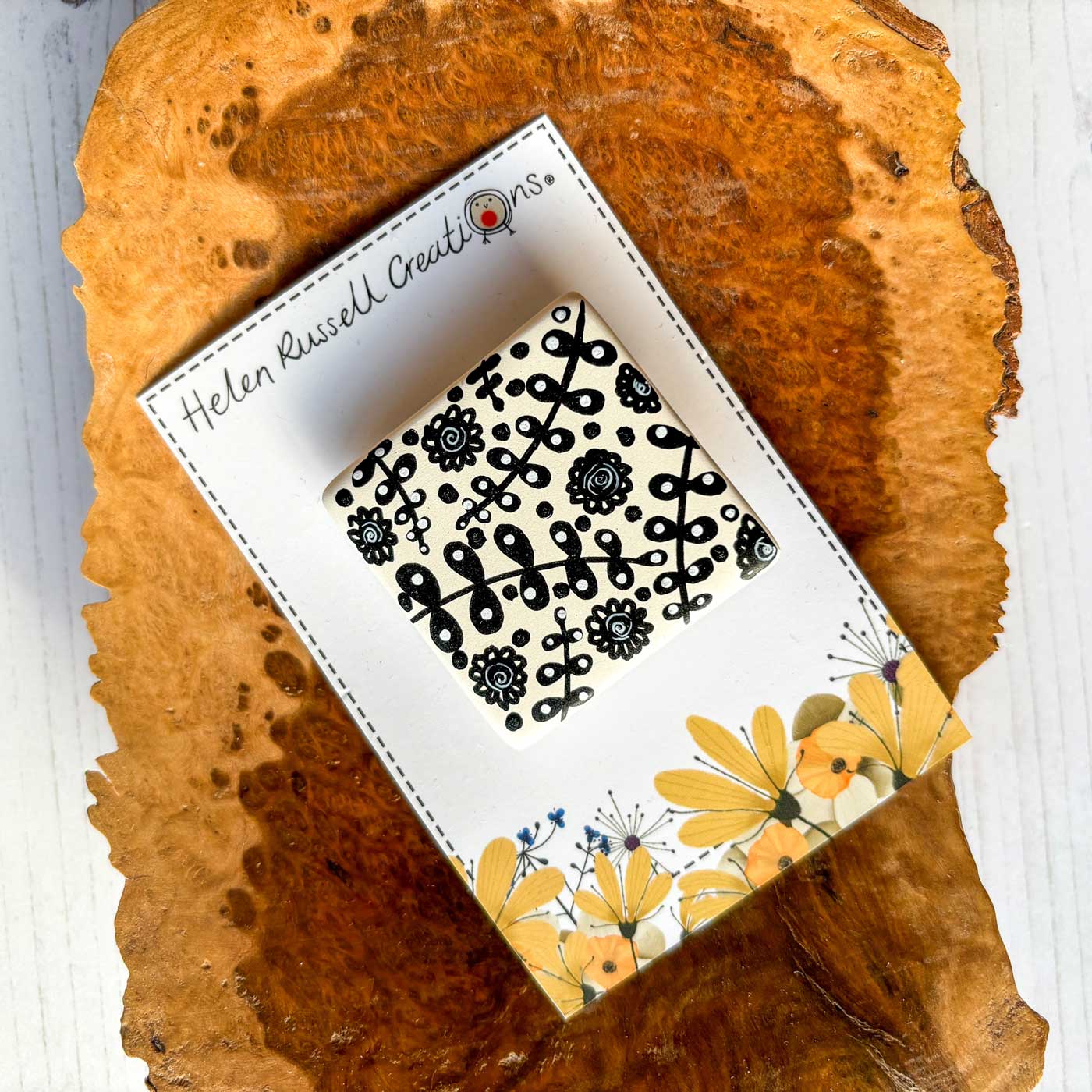 square ceramic brooch hand painted with a simple black and white leaf design